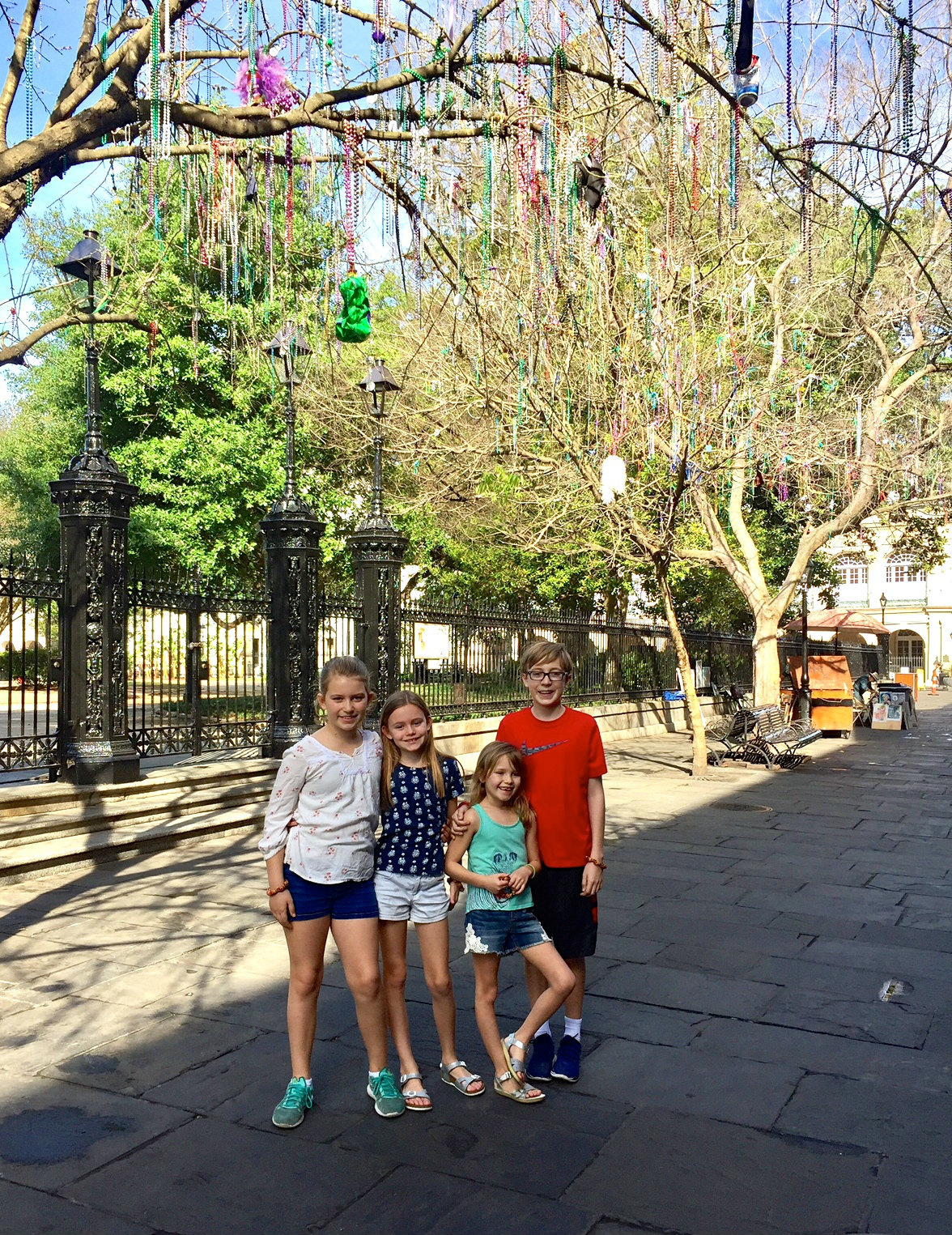 Kids underneath hanging mardi gras beads in Jackson Square in the French Quarter in New Orleans.
