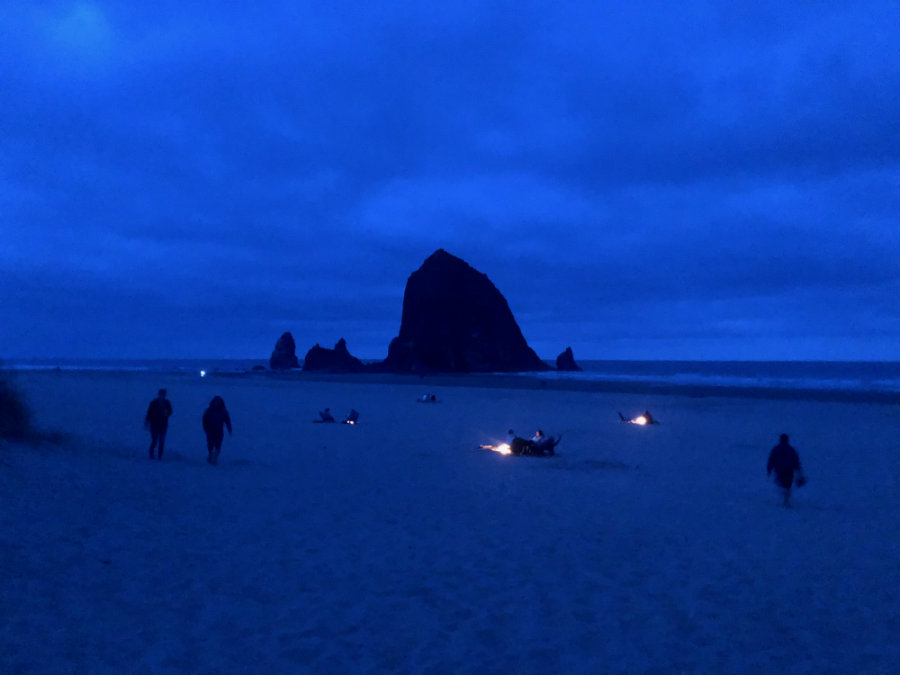 Haystack Rock at night with campfires in Cannon Beach